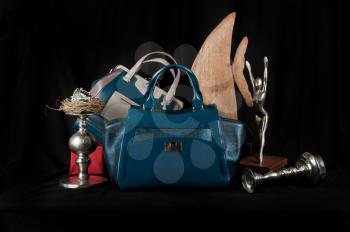 Fashionable handbag  with jewelry and different items for composition on black background. 