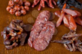 Blurred pronounced background of different sausage and meat on a celebratory table with spices and vegetables