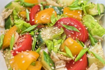 Bulgarian salad from pepper, cucumbers, tomato, green onion with sesame and oil