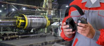 Worker with protective headphone at man hands at industrial factory