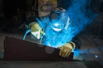 worker welding metal with sparks at factory