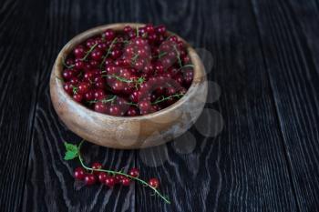 Fresh red currants in plate on wooden table