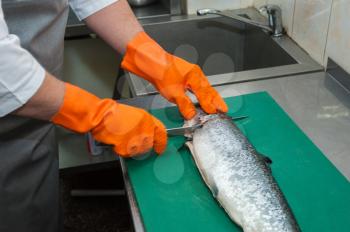 Chef cutting salmon fish with knife