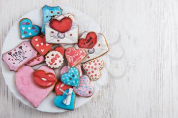 Gingerbreads for Valentines Day at plate on white wooden background