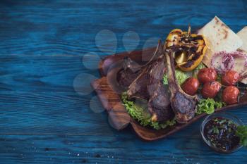 Grilled lamb meat with vegetable on a blue wooden background