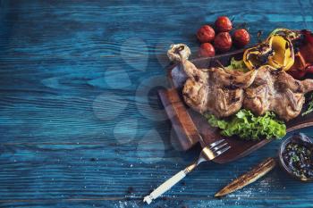 Grilled quail meat with vegetable on a blue wooden background