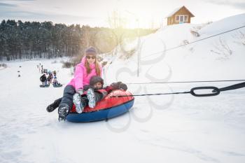 Mother and her son having fun on a snow tube, at beauty winter day