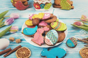 Tulips and gingerbread cookies on white and blue wooden background for Easter.