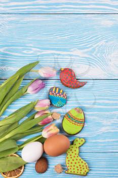 Tulips and gingerbread cookies on white and blue wooden background for Easter.