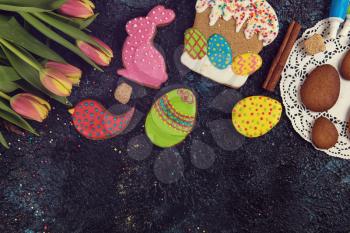 Tulips and gingerbread cookies on darken concrete background for Easter.