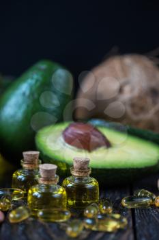 Oil of avocado with fish oil pills and peanut - source of omega 3 on a dark wooden background