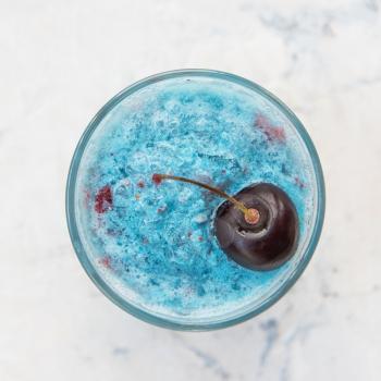 Blue cherry smoothie on a white concrete background. Square cropping
