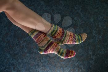 Woman legs in wool knitted socks on a grey background