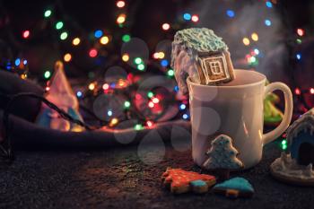 Christmas cookies and cup of tea on dark color bokeh lights background