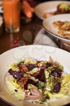 Healthy vegeterian food on brown wood board. Salad from beet with dried tomatoes and cabbage