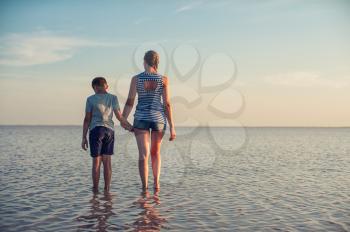 Mother and her son on salty lake with beauty sunset