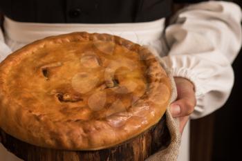 Pie from potato meat cheese and vegetables. Freshly baked pie in hands of woman in uniform