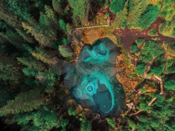 Beautiful Geyser (blue, silver) lake with thermal springs that periodically throw blue clay and silt from the ground. Aerial drone view. Aktash, Altai mountains, Russia