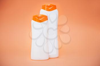 Different cosmetic bottles of cream, soaps, foams or shampoo on orange background.