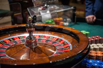 Casino, gambling and entertainment concept - roulette table and stack of poker chips