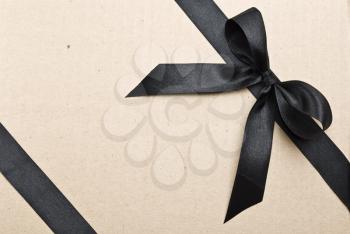 Royalty Free Photo of Black Satin Ribbon and Bow on a Cardboard Background