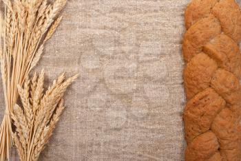 Bread with wheat  ears  on burlap background