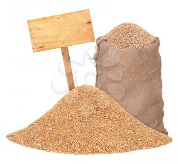 Heap of wheat grains with wooden price tag and sack