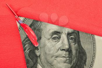 Benjamin Franklin macro peeking through cutting red paper 