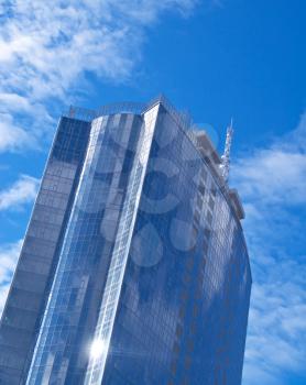 Beautiful Futuristic skyscraper made of Glass and steel with blue sky reflection