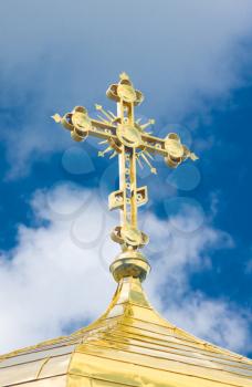 Close-up of Golden crucifix and Cupola of Orthodox church and blue sky with clouds