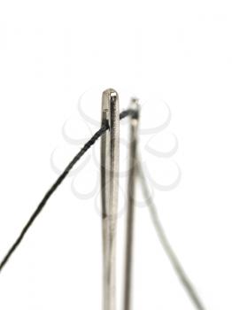 Needles with black thread over white (shallow DOF, focused on front needle)