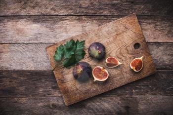 Tasty Figs on chopping board and wooden table. Autumn season food photo