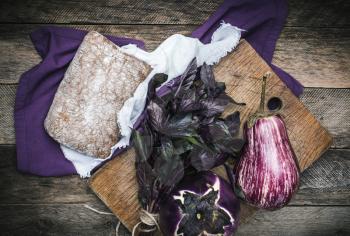 Aubergines basil and bread on chopping board and wood. Rustic style and autumn food photo