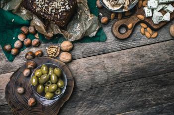 nuts mushrooms bread and olives on wooden table  in rustic style