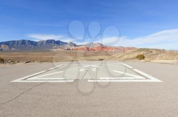 Helicopter pad against the dry landscape and red rock formations of the Mojave Desert.