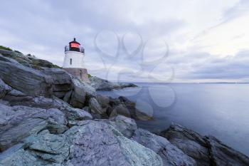 Lighthouse on a rocky shore at sunset.