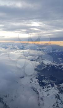 Beautiful top view on the evening Alps, covered with snow and clouds