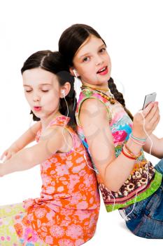 Royalty Free Photo of a Two Girl Sitting Back to Back Listening to Music on their Mp3 Player