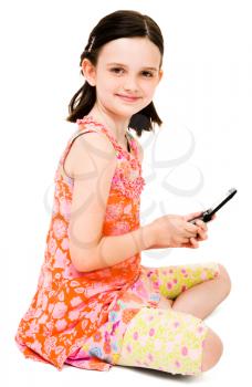 Royalty Free Photo of a Young Girl Sitting on the Floor Text Messaging on her Mobile Phone