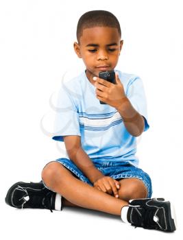 Royalty Free Photo of a Young Boy Sitting on the Floor Texting on his Phone