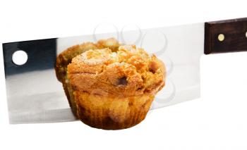Meat cleaver cutting a cupcake isolated over white
