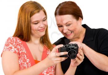 Two women holding a camera and smiling isolated over white