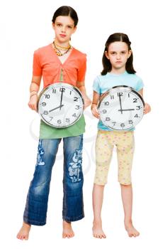 Two girls holding clocks isolated over white