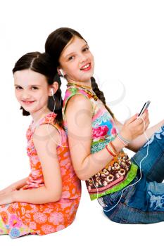 Portrait of girls listening to MP3 player and smiling isolated over white