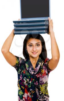 Woman carrying a stack of laptops and smiling isolated over white