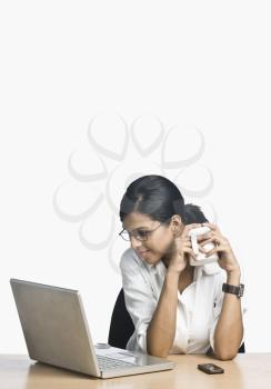 Businesswoman working on a laptop and drinking coffee