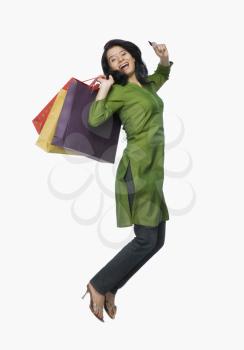 Young woman jumping with shopping bags and a credit card