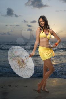 Portrait of a female fashion model holding a parasol on the beach