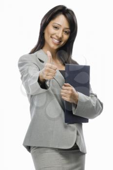 Portrait of a businesswoman holding files and showing thumbs up