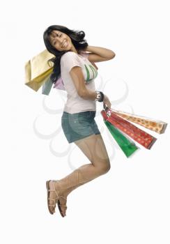 Young woman carrying shopping bags and jumping